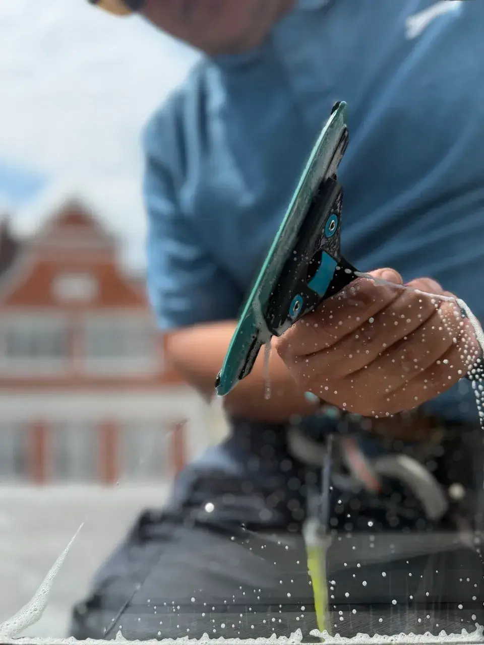 Close up of a squeegee pulling water from glass